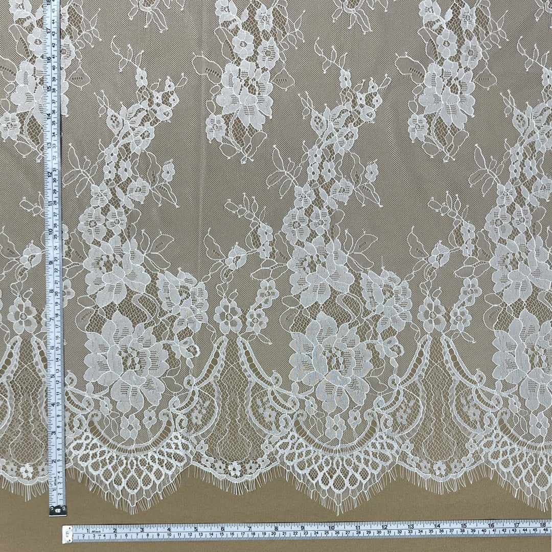 close-up of Ivory/Off white Chantilly lace fabric with floral design and scalloped eyelash edge, with measuring tapes for scale- LaceUSA-GDF-11
