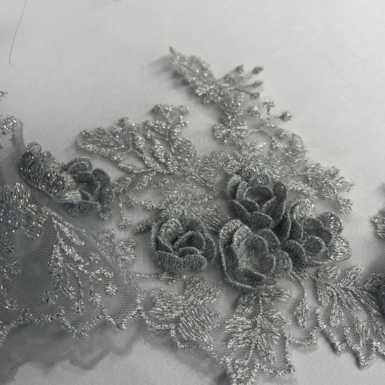  Closeup of Silver lace trim with 3D rose motifs embroidered with metalic thread on 100% polyester net mesh, on a white background. LaceUSA #21853W
