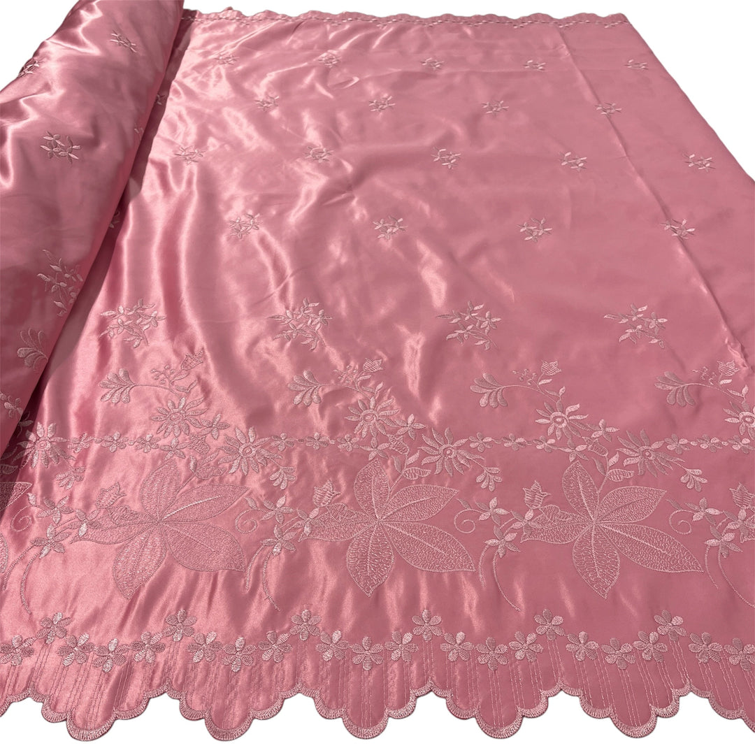 Dusty Rose satin fabric with delicate floral embroidery and a scalloped edge, shown partially rolled on the left against a white background.