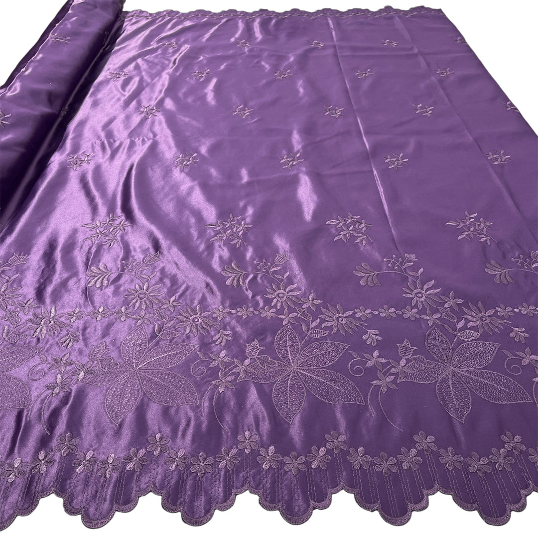 Plum satin fabric with embroidered floral patterns and a scalloped border, shown partially rolled on the left side against a white background.