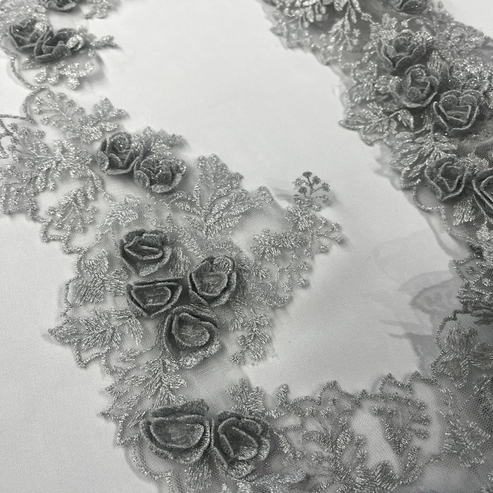 Silver lace trim with 3D rose motifs embroidered with metalic thread on 100% polyester net mesh, on a white background. LaceUSA #21853W