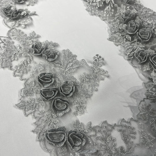 Silver lace trim with 3D rose motifs embroidered with metalic thread on 100% polyester net mesh, on a white background. LaceUSA #21853W