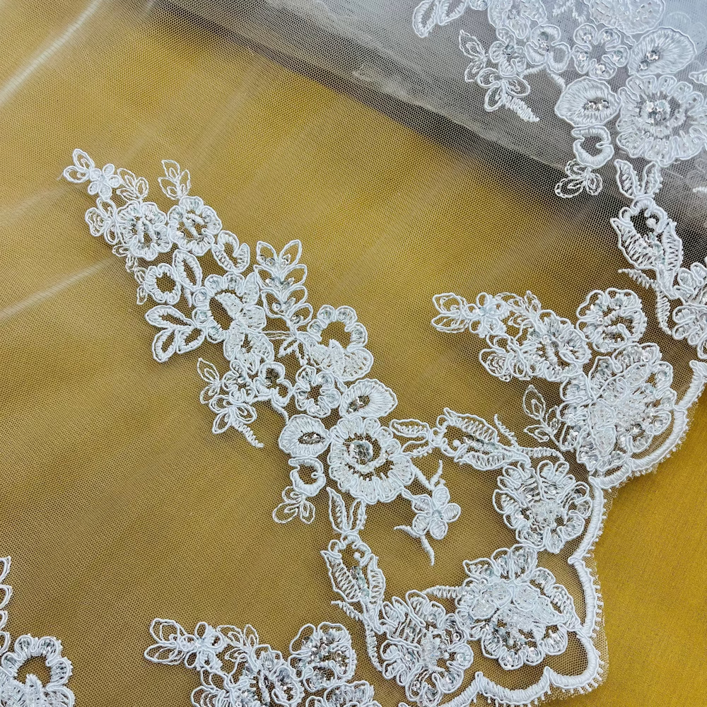 Closeup of white Beaded & Corded Bridal Lace Fabric Embroidered on 100% Polyester Net Mesh | Lace USA